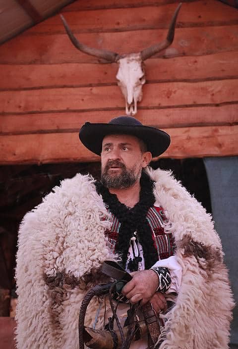 Hagyományos román pásztor szarvasmarha koponyával díszített istálló előtt, Kakukkmező Vadaspark